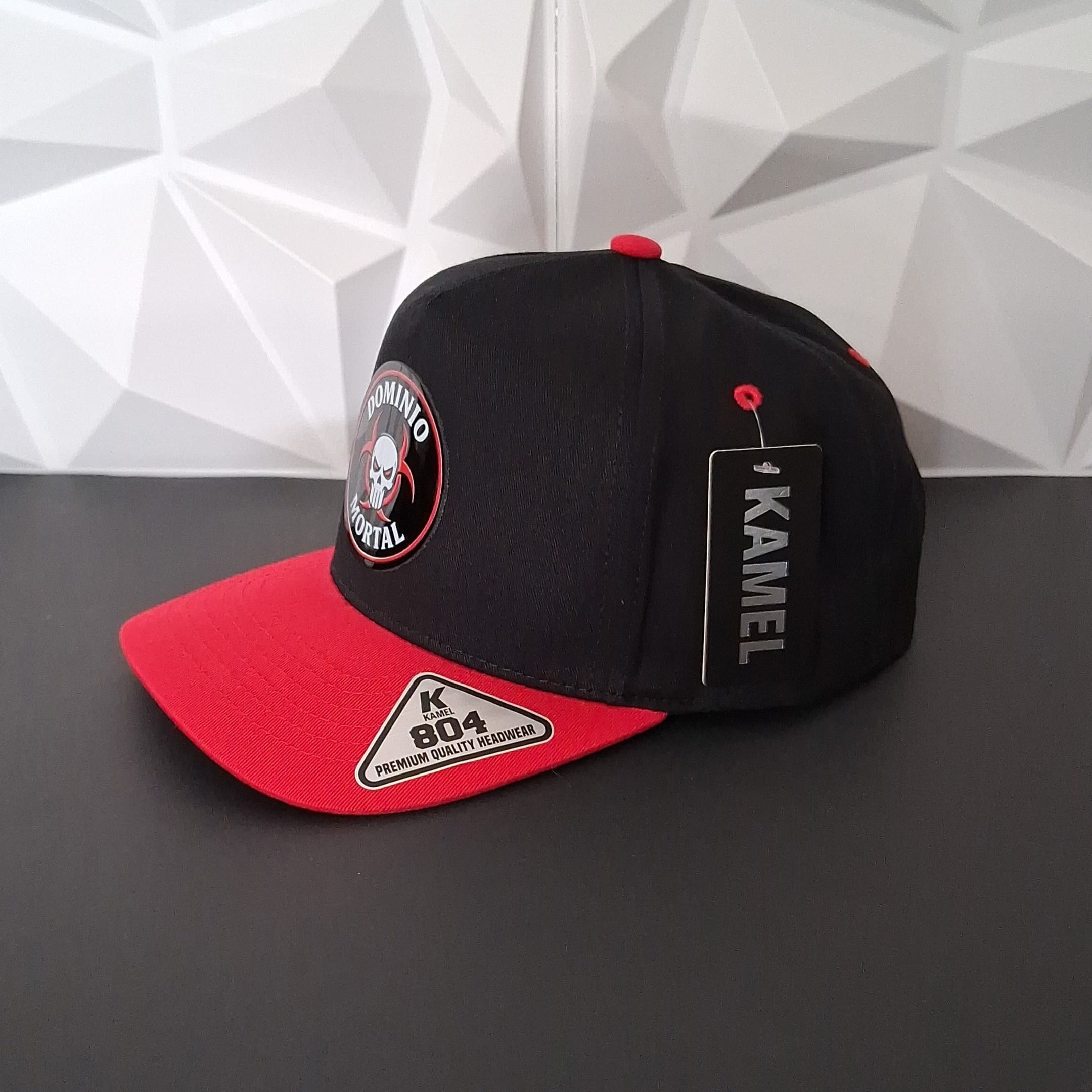 Black and red cap with branding on a geometric patterned wall background